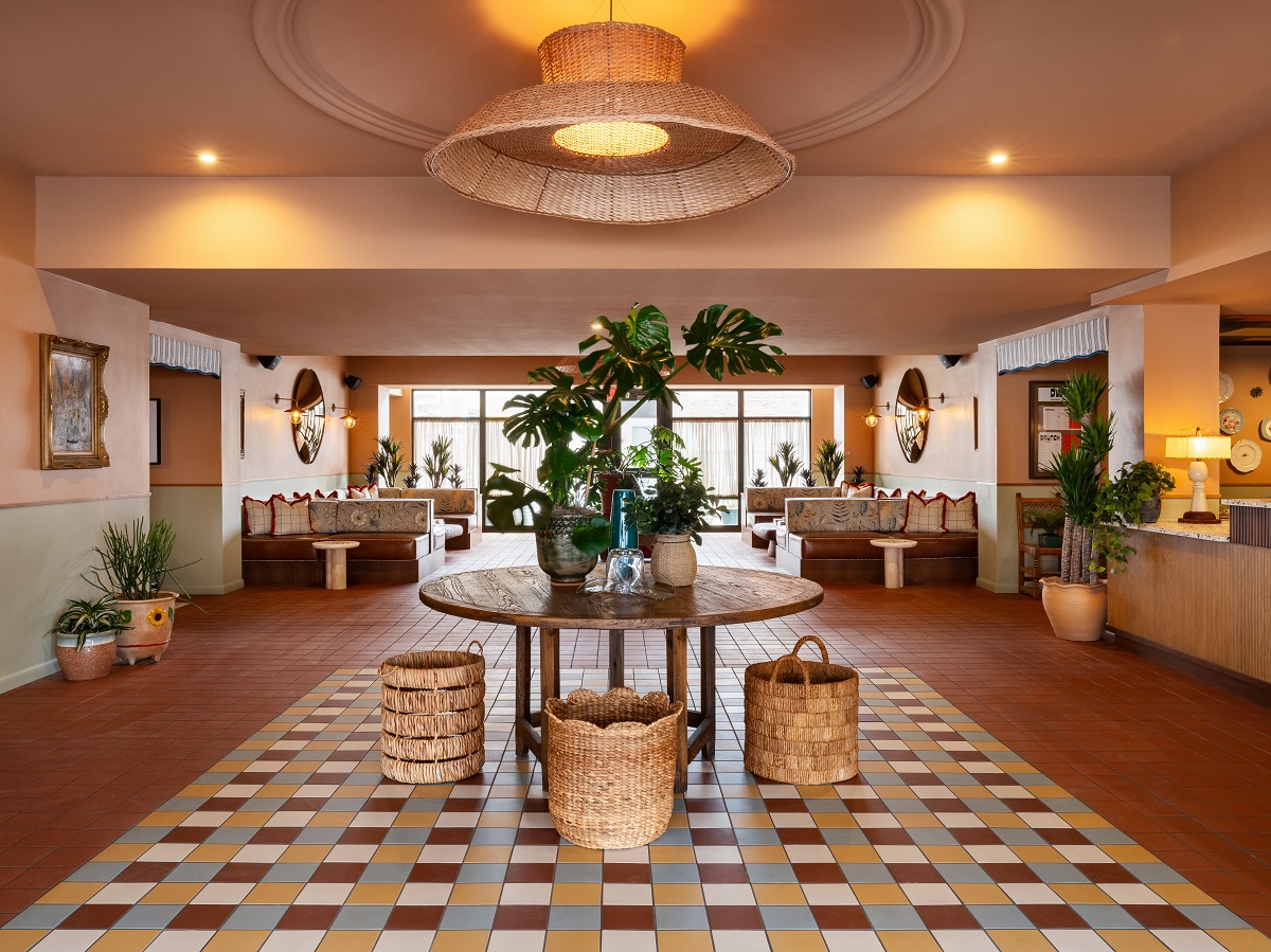 vestíbulo del hotel con suelo de baldosas, mesa de madera, plantas y cestas